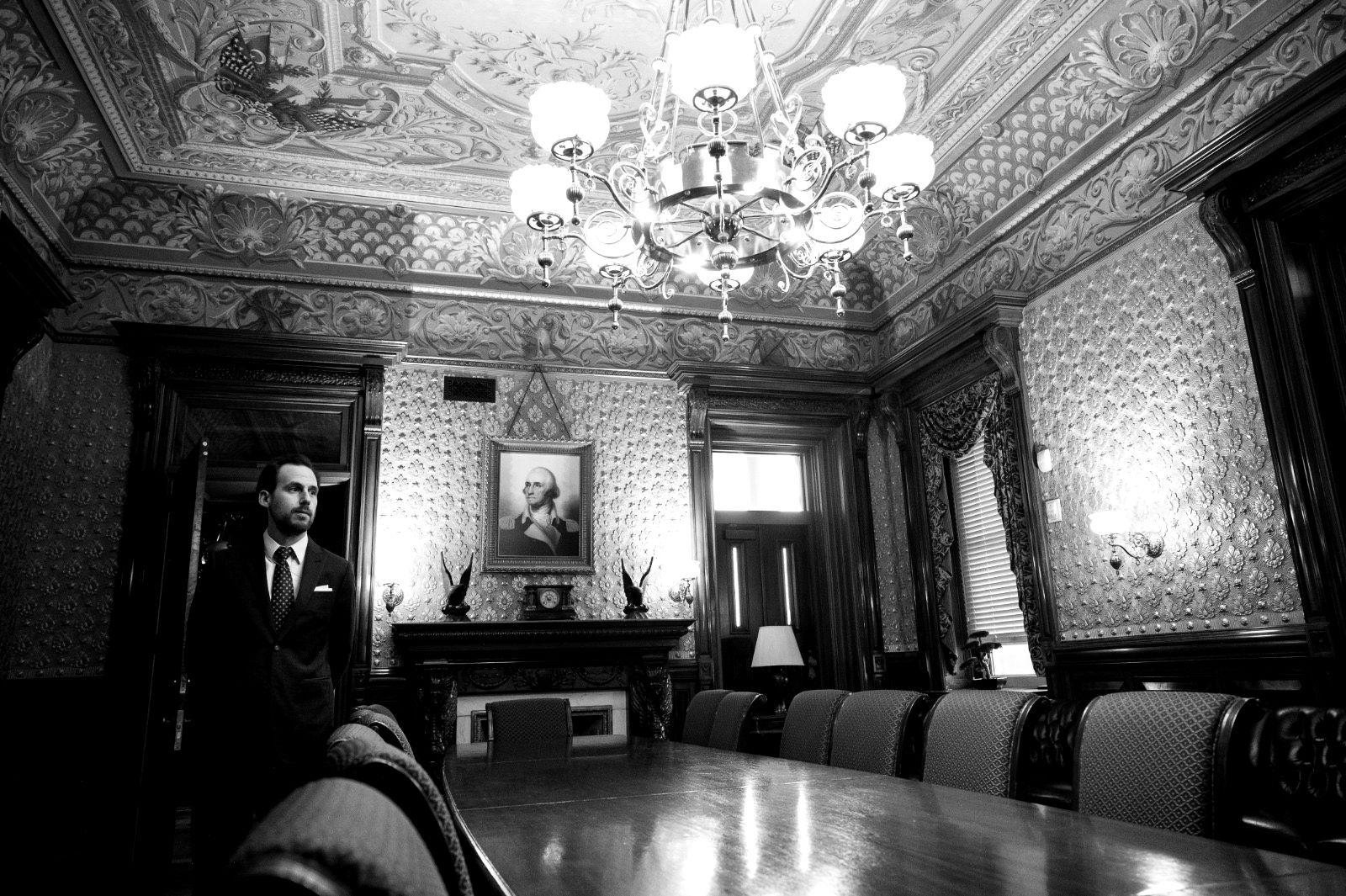 A panelled state room in Washington, chandelier lit, a man standing in the doorway