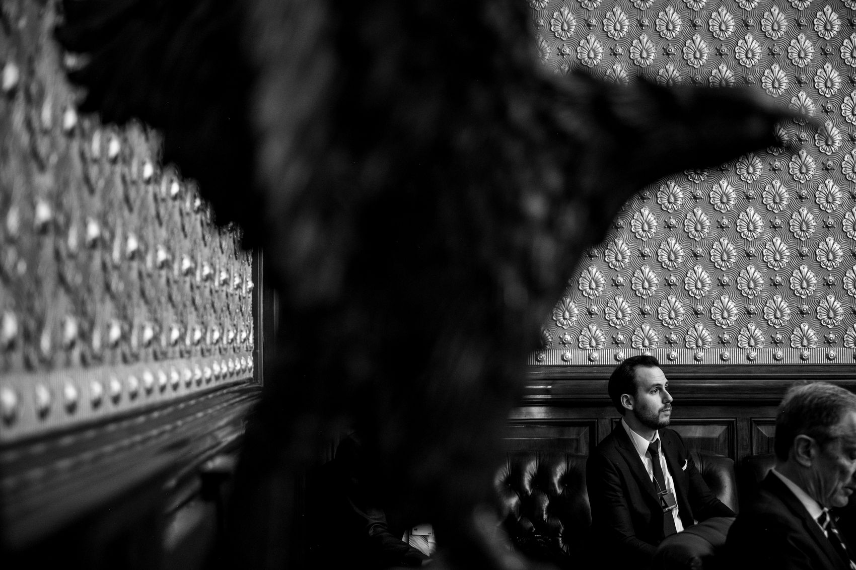 A man seated in a gilded state room, seen past a carved eagle