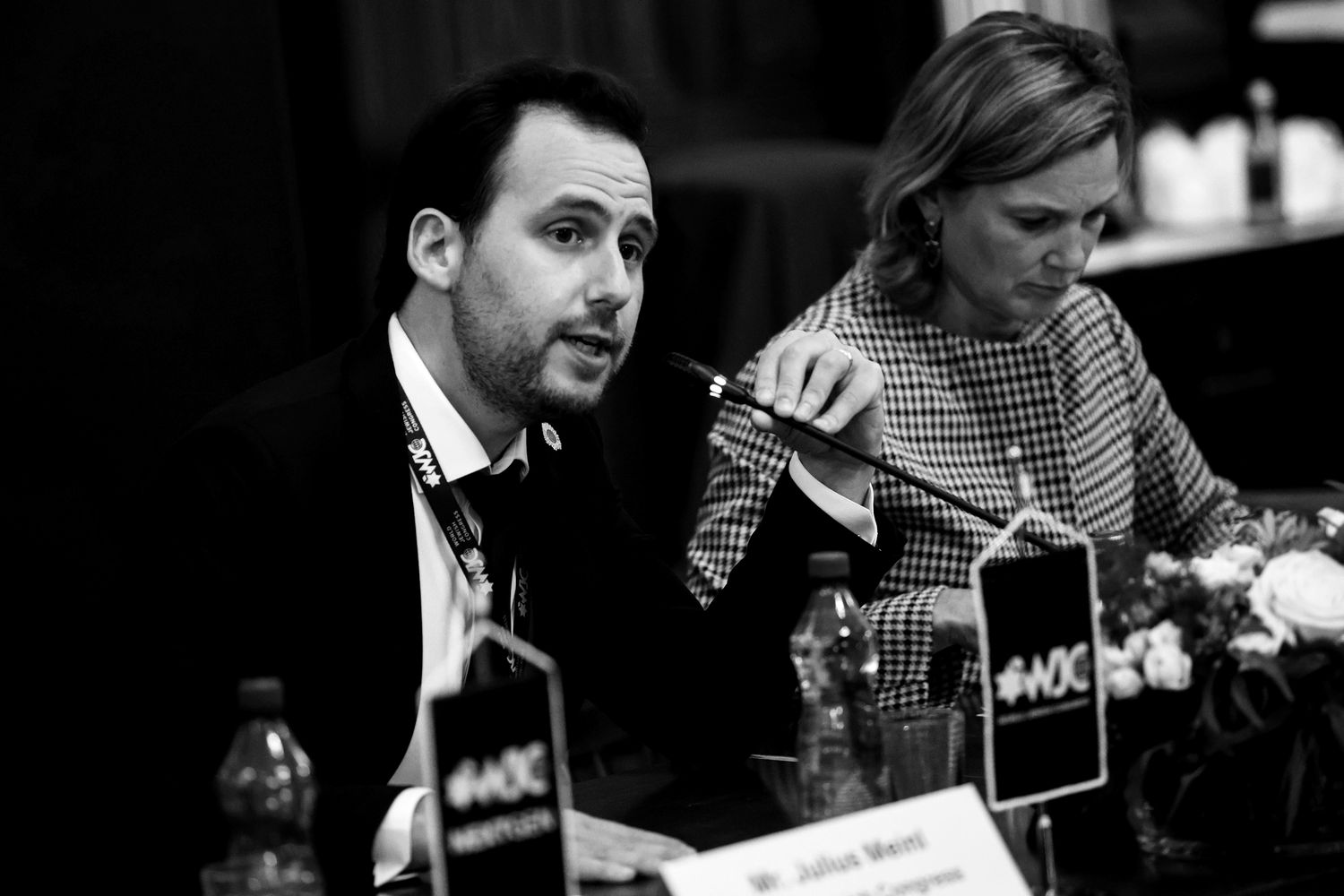 A man speaking into a microphone at a conference table